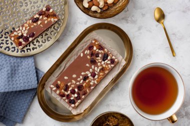 El yapımı, sedir fıstığı ve kızılcıklı sütlü çikolata bir fincan çayın yanında duruyordu.