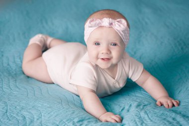 Saç bandı takmış yeni doğmuş bir kız mavi bir battaniyenin üzerinde yatıyor.