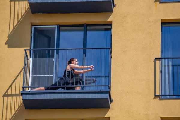 Kadınlar dairenin balkonunda spor yapıyor. Salgın sırasında evde kal.