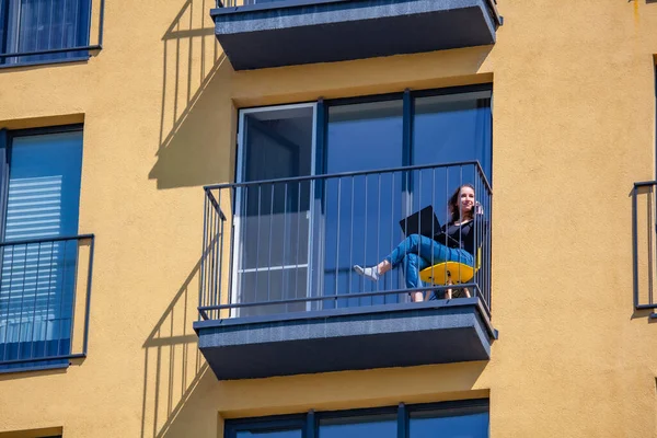 Balkonda dizüstü bilgisayarda çalışan bir kadın. Evden çalış.