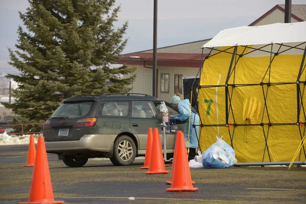 Helena, Montana / ABD - 20 Mart 2020: Kafkasyalı bir kadın sağlık görevlisi Coronavirus Covid-19 servis çadırında nabız oksimetresiyle kan oksijeni seviyesini ölçerek bir hastayı muayene ediyor. 