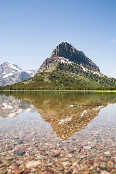 Montana 'daki Buzul Ulusal Parkı' nda Swiftcurrent Gölü üzerinde karlı bir dağ suyu yansıması. Grinnell Point, Babb, Montana 'daki Lewis Sıradağının bir parçasıdır..