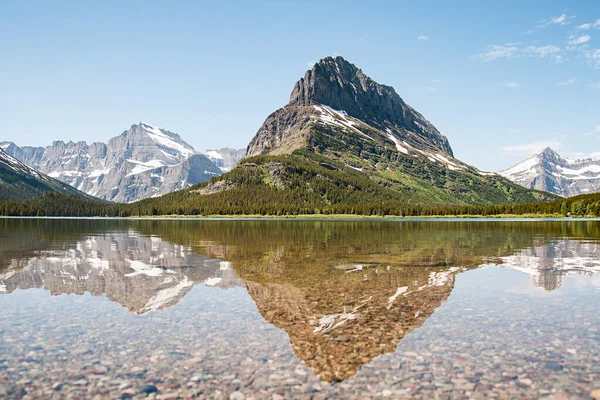 Montana 'daki Buzul Ulusal Parkı' nda Swiftcurrent Gölü üzerinde karlı bir dağ suyu yansıması. Grinnell Point, Babb, Montana 'daki Lewis Sıradağının bir parçasıdır..