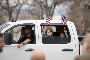 Helena, Montana - April 19, 2020: Children girls holding and waving American flag from a vehicle at the protest at the Capitol to reopen business and the government shutdown over Coronavirus. clipart