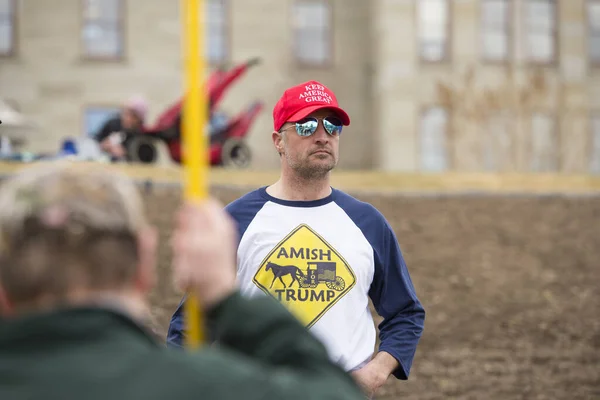 Helena, Montana - 19 Nisan 2020: Covid-19 Coronavirus salgını nedeniyle hükümetin kapanmasını protesto eden kırmızı Keep America Great şapkalı adam. Ayrıca Amish marka Trump tişörtü giyiyor..