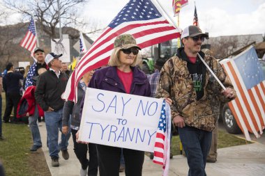 Helena, Montana - 19 Nisan 2020: Koronavirüs hükümetinin kapatılması üzerine düzenlenen mitingde Amerika bayrakları tutan bir grup göstericiyle birlikte zorbalık işaretine hayır deyin.