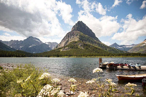 Buzul Ulusal Parkı 'ndaki Mountain Peak Manzarası Grinnell Point ve Swiftcurrent Gölü. Yüzeyinde parlak mavi bir gökyüzü olan kayıklar suya yanaştı..