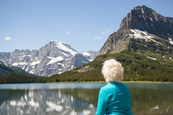Sarışın kadın Montana 'nın dağ manzarasına bakıyor. Buzul Ulusal Parkı 'nın güzel dağlarına bakan 70 yaşındaki bir turist. Yaşlı bir gezgin ve aktif bir yaşam tarzı var. Boşluğu kopyala.