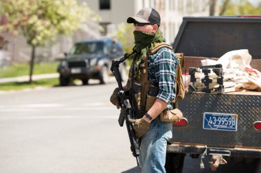 Helena, Montana - May 20, 2020: An armed man, militia member, protest at the Capitol building, holding a semi-automatic weapon in a street at the capitol, member of The Continentals with a gun. clipart