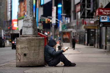New York City, New York / ABD - Nisan 12020: New York 'ta karantina Coronavirus salgını sırasında evsiz insanlar gazete okuyor, dışarıda yemek yiyor, boş şehirde dolaşıyor.