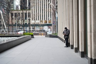 New York City, New York / ABD - Nisan 12020: New York 'ta salgın sırasında turistler olmadan boş Rockefeller Plaza' da ayakta duran adam, radyo şehri müzikholü.