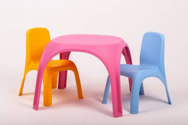 Sarı plastik çocuk masası ve beyaz arka planda iki sandalye.