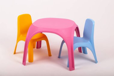 Sarı plastik çocuk masası ve beyaz arka planda iki sandalye.