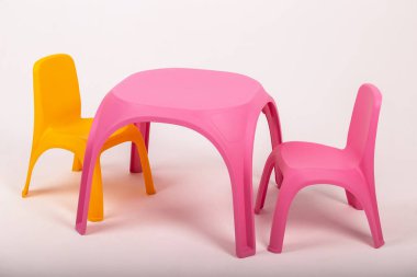 Sarı plastik çocuk masası ve beyaz arka planda iki sandalye.