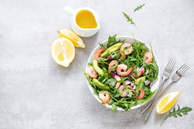 Karides avokado ve roka salatası, sağlıklı ve besleyici yemek tarifi, servis masasının üzerinde hazır yemek ve bazı malzemeler.