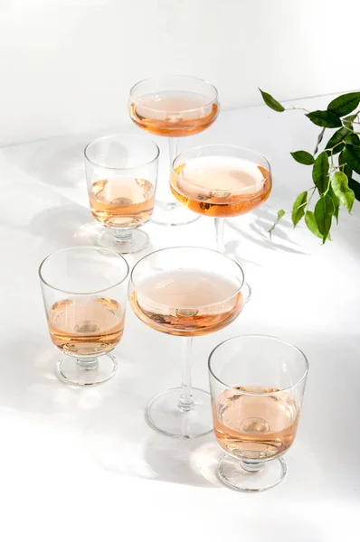 Rose wine assortment, front view of various wine glasses full of rose wine, standing on a white table surface  reflecting soft sunshine rays