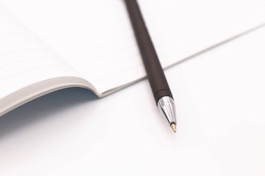 Beyaz arkaplanda siyah dolmakalem ve defter