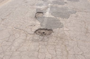 Delikleri ve çatlakları olan eski asfalt yolu