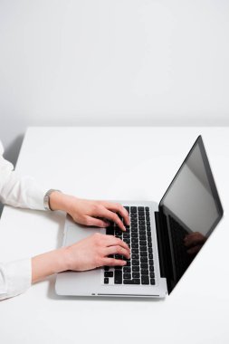  Kadın elleri dizüstü bilgisayarın klavyesinde, beyaz bir masada ve beyaz bir duvarda yatıyor.