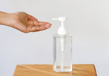 Önleyici virüs ve mikrop konseptinde beyaz arka planda alkol jeli şişesi olan el..