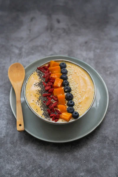 Fresh mango smoothie bowl made from mango, banana, kiwi and yogurt, selective focus