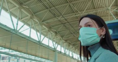 Tren istasyonunda maskeli bir kadın bekliyor.