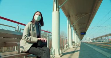 Tren istasyonunda maskeli bir kadın bekliyor.