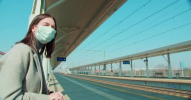 Tren istasyonunda maskeli bir kadın bekliyor.