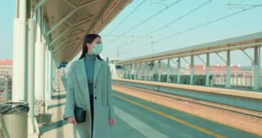 Tren istasyonunda yürüyen maskeli bir kadın.