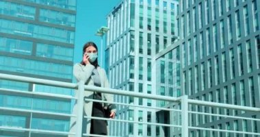 İş bölgesinde yüz maskeli bir kadın telefonla konuşuyor.