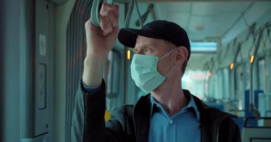 Tramvayda seyahat eden maskeli adam.