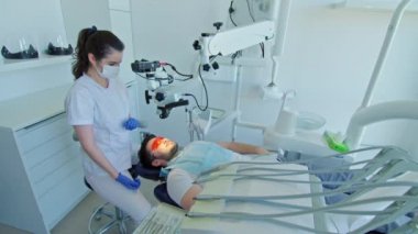 Diş hekimi hastaların dişlerini diş mikroskobuyla inceliyor.