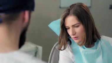 Diş hekimi ve hasta muayenehanesinde konuşuyor.