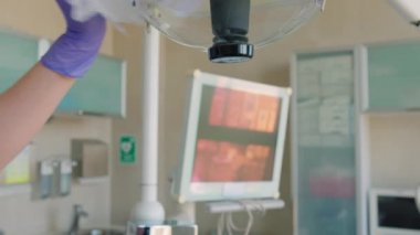 Dişçi, dişçi muayenehanesinde lamba temizliyor.