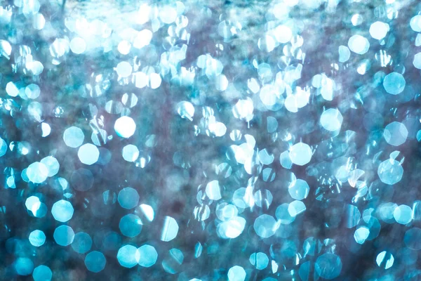 Bokeh Background.圣诞蓝灯。水在阳光下变得模糊，抽象的雪花，冬天的白色闪光，钻石的光芒，模糊的背景与焦距 — 图库照片