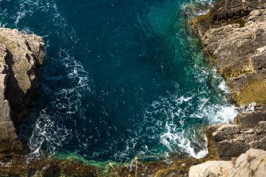 Mavi denizin üzerinde kayalık bir uçurum