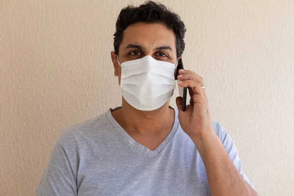 adult wearing disposable surgical mask with phone