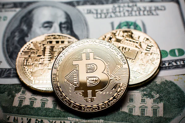 Bitcoin. Bitcoins de oro en un billete de cien dólares de cerca — Foto de Stock