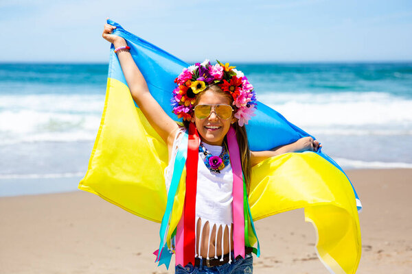 Украинка несет на берегу моря синий и желтый флаг Украины
