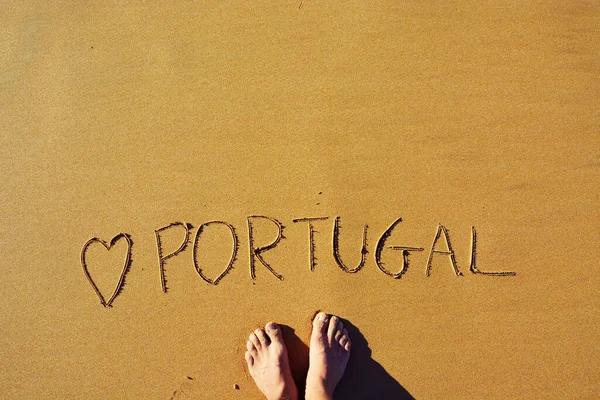 Homem em pé no topo de um amor esculpido Portugal na areia — Fotografia de Stock