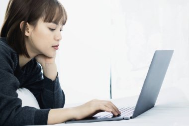 Evde dizüstü bilgisayarda çalışan güzel Asyalı kadın. Sosyal uygulamaları ve çalışmaları kontrol eden kadın. Ev konseptinden çalışma..