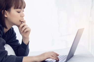 Evde dizüstü bilgisayarda çalışan güzel Asyalı kadın. Sosyal uygulamaları ve çalışmaları kontrol eden kadın. Ev konseptinden çalışma..