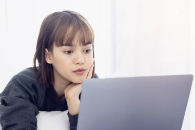 Evde dizüstü bilgisayarda çalışan güzel Asyalı kadın. Sosyal uygulamaları ve çalışmaları kontrol eden kadın. Ev konseptinden çalışma..