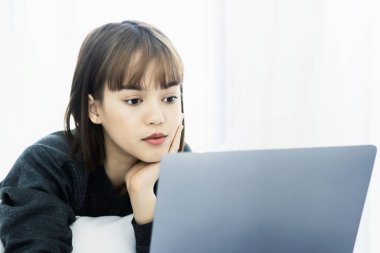 Evde dizüstü bilgisayarda çalışan güzel Asyalı kadın. Sosyal uygulamaları ve çalışmaları kontrol eden kadın. Ev konseptinden çalışma..