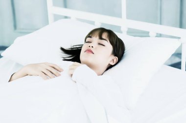 Asyalı kadın tatilde yatak odasında beyaz yastıkta uyur..