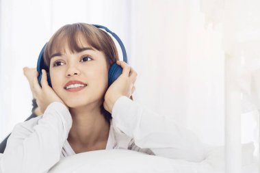 Güzel Asyalı kadınlar uzanıp sartphone 'da internete radyo ile müzik dinlerler. Yaşam tarzı kavramı. Renk tonu