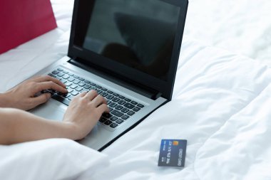 İnternetten ödeme yapan Asyalı kadın. İnternet üzerinden alışveriş yapan kişi kredi kartı ve dizüstü bilgisayarla evde online alışveriş yapıyor..