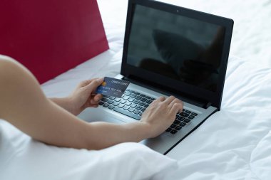 İnternetten ödeme yapan Asyalı kadın. İnternet üzerinden alışveriş yapan kişi kredi kartı ve dizüstü bilgisayarla evde online alışveriş yapıyor..