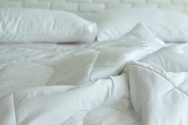Yatağı beyaz yastıkla, battaniyeyi de sabah yatak odasında doğal ışık ile kirletti.,
