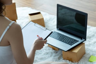 Online alışveriş için dizüstü bilgisayarla çalışan Asyalı kadınlar evde paketleme için kutu, Online alışveriş için Küçük İş Başlat. Alışveriş merkezi iş konsepti.